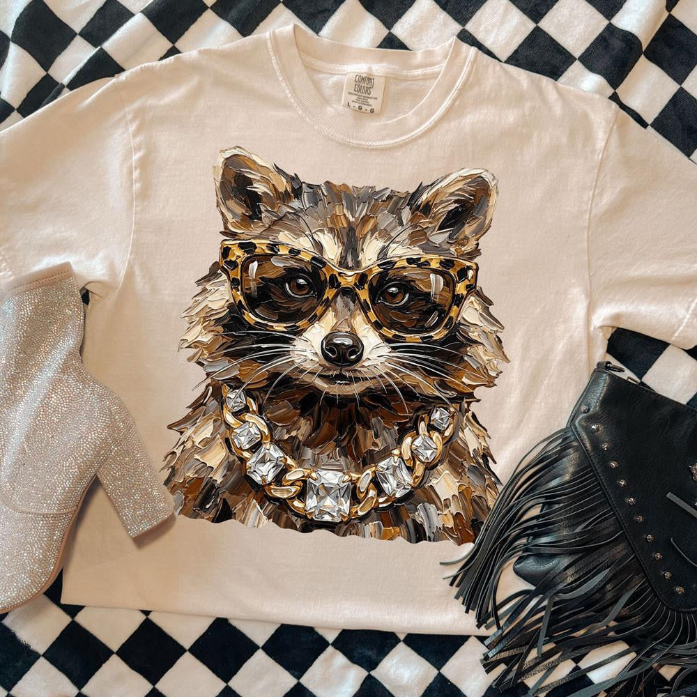 Glam raccoon with leopard glasses and jeweled chain on an ivory Comfort Colors tee